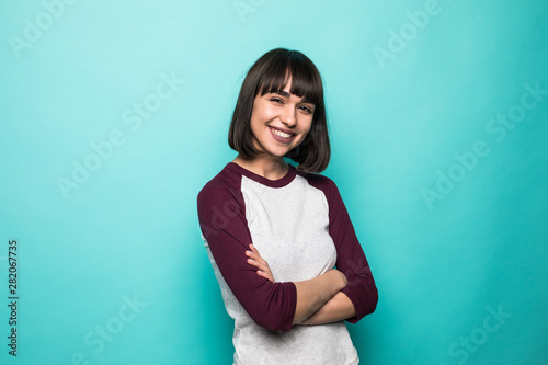 Portrait of the beautiful young woman with crossed hands on the green background