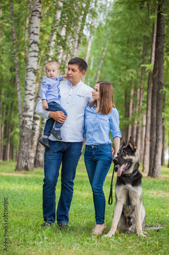 Family walk: mom, dad and son with his dog in the forest. German shepherd is the best friend of the child. © izida1991