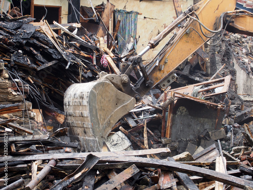 Hydraulic crusher excavator backoe machinery working on a demolition site clearing debris