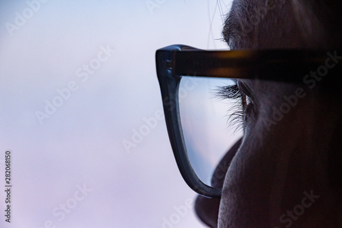 Close up of eye with glasses looking thoughtfully out of the windows
