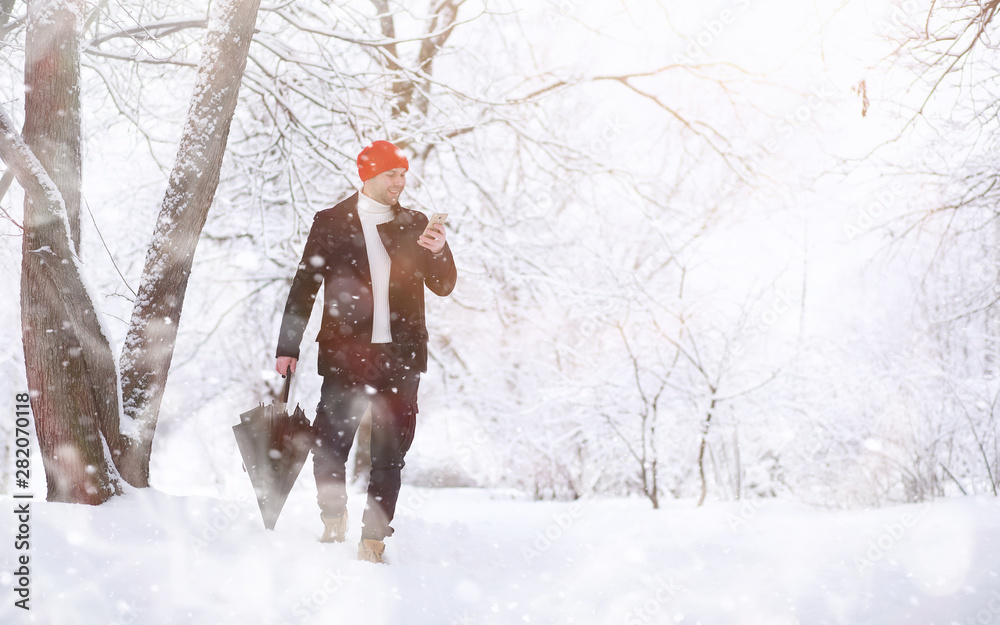 A man on a walk in the park. Young man with in the winter snowfall.