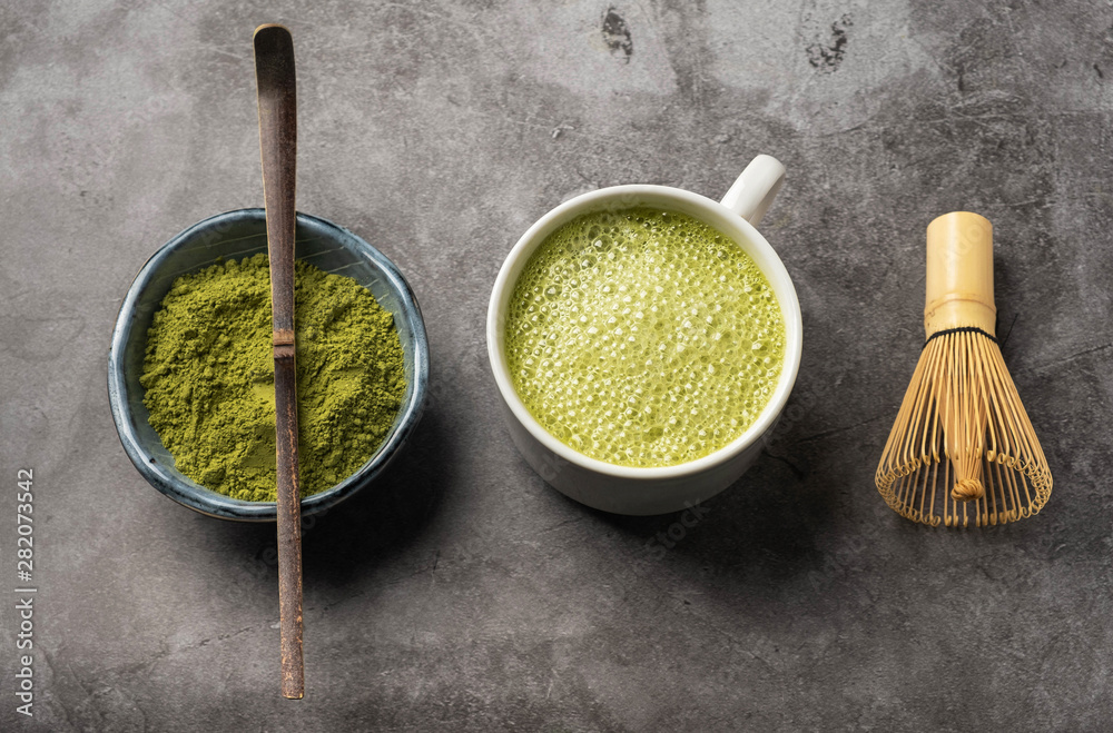 Japanese matcha green tea powder, a healthy natural product, antioxidant. Bamboo spoon and whisk. Gray background, close-up, top view. Japanese matcha green tea powder, a healthy natural product, antioxidant. Bamboo spoon and whisk. Gray background, close-up, top view.