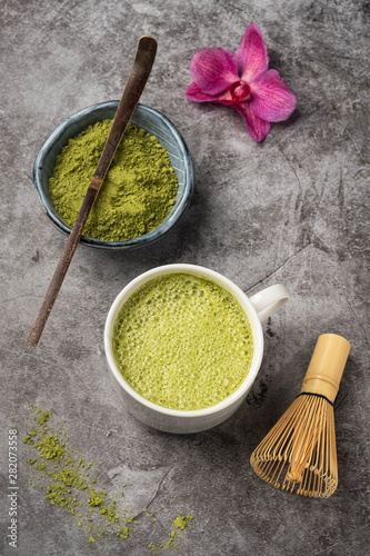 Japanese matcha green tea powder, a healthy natural product, antioxidant. Bamboo spoon and whisk. Gray background, close-up, top view.