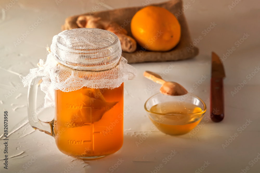 Homemade fermented drink Kombucha in glass jar with lemon, honey and ginger on a wooden table. Close-up Homemade fermented drink Kombucha in glass jar with lemon, honey and ginger on a wooden table. Close-up