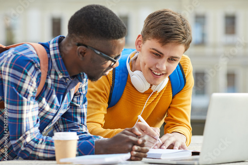 Canvastavla Portrait of two international college students doing homework together outdoors