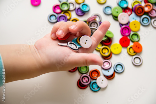 Cuadro en lienzo a child's hand holds many round buttons