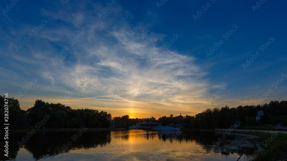Panorama of the evening sky with clouds in Yaroslavl. The setting sun is reflected in the water of the Kotorosl River.