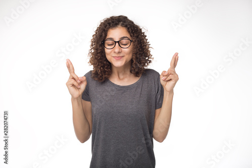 A black woman of mixed race with shaggy hairstyle makes a wish fingers crossed. Happy Indian girl in the studio on a white background. 