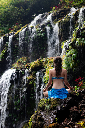 Young Caucasian woman meditating  practicing yoga at waterfall. View from back. Banyu Wana Amertha waterfall Wanagiri  Bali  Indonesia. 
