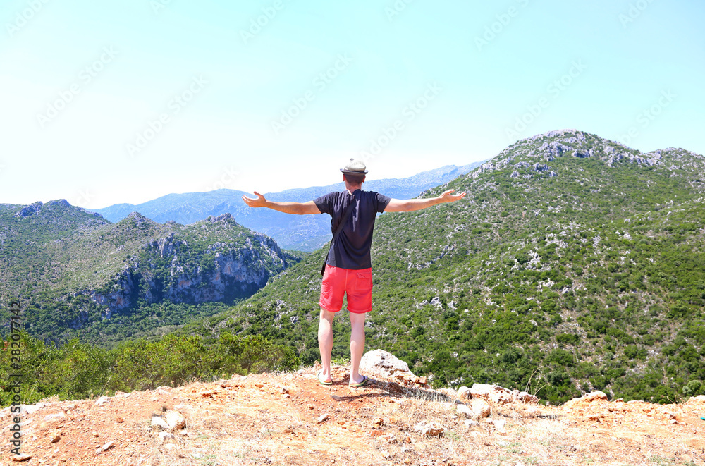 man standing with open hands in front of the mountains at Lakonia Peloponnese Greece