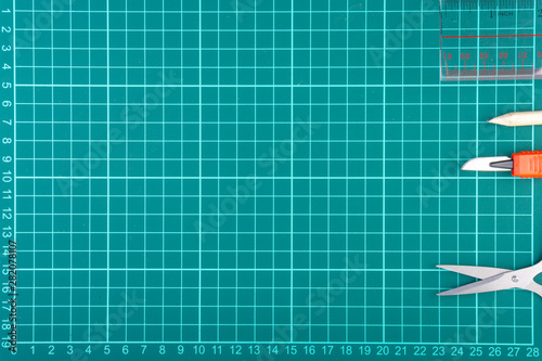 Knives cutter, pencil, scissor and stationary on white green cutting mat background. Selective focus and copy space