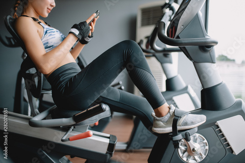 Beautiful asian women take a rest playing a smartphone after workout at gym