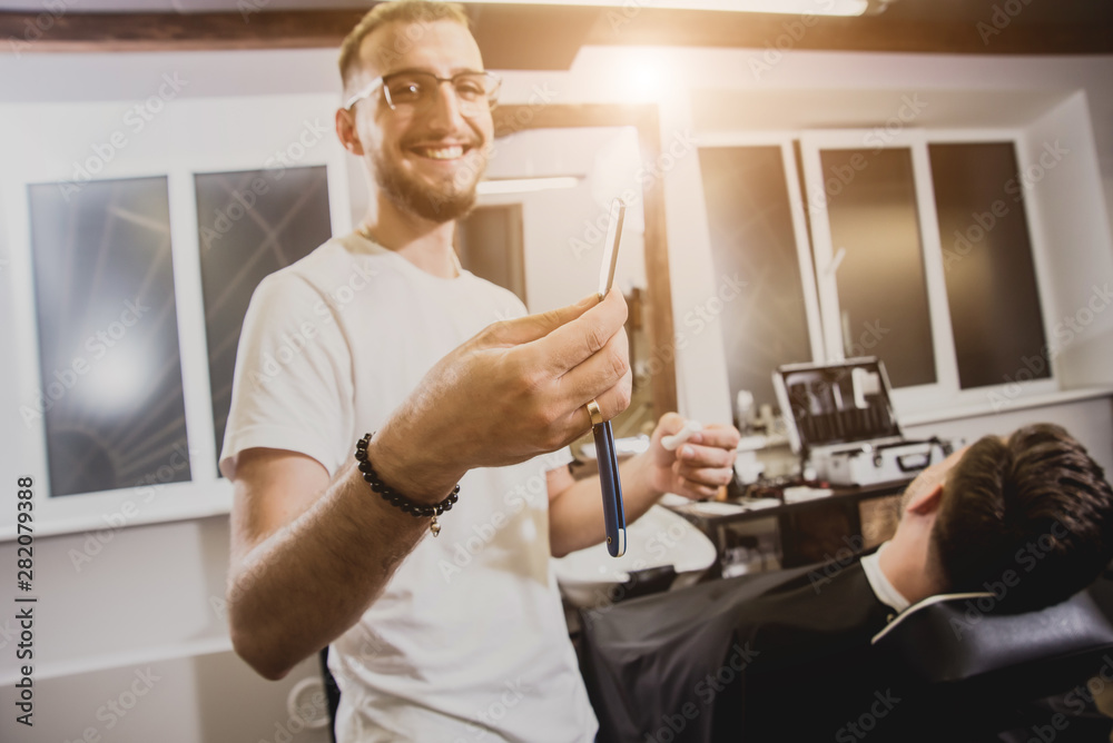 Young man with trendy haircut at barber shop. Barber does the hairstyle and beard trim. Young man with trendy haircut at barber shop. Barber does the hairstyle and beard trim.