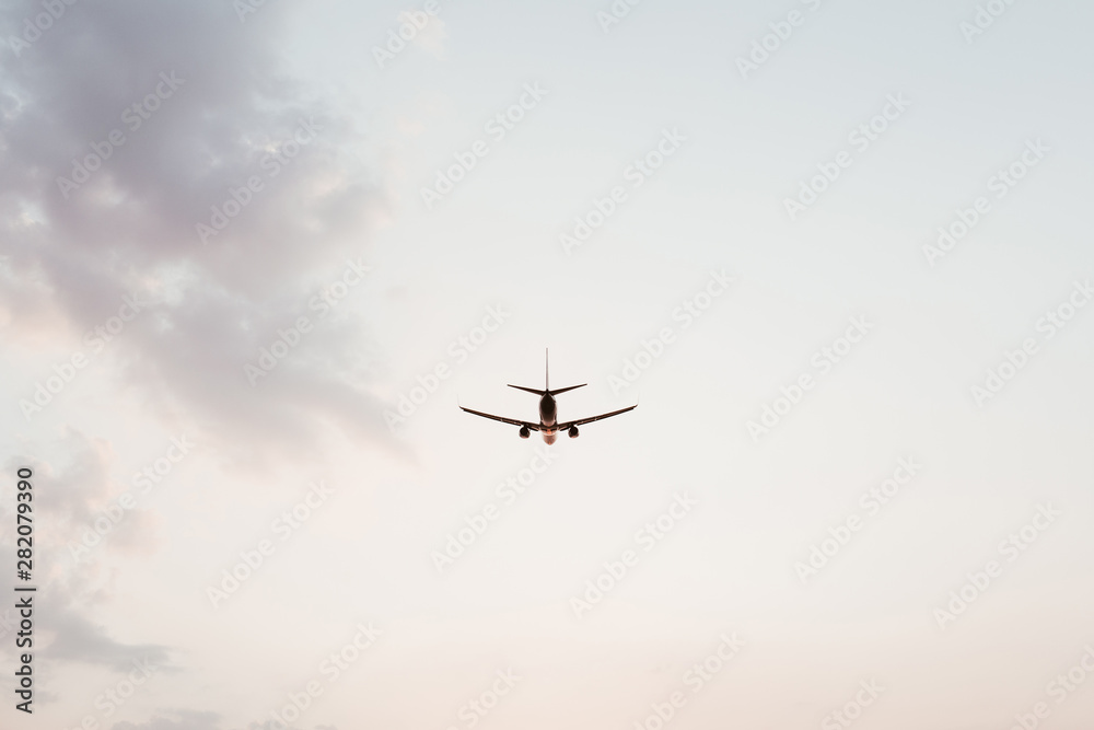 Airplane flying in the sky at sunset with pink purple clouds. Travel, vacation and holiday concept. Vintage and retro tones filter. Minimalistic background. Airplane flying in the sky at sunset with pink purple clouds. Travel, vacation and holiday concept. Vintage and retro tones filter. Minimalistic background.