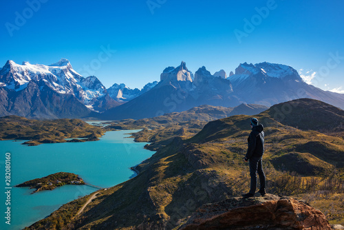 Hiker at mirador condor enjoying amazing view of Los Cuernos rocks and Lake Pehoe in Torres del Paine national park, Patagonia, Chile