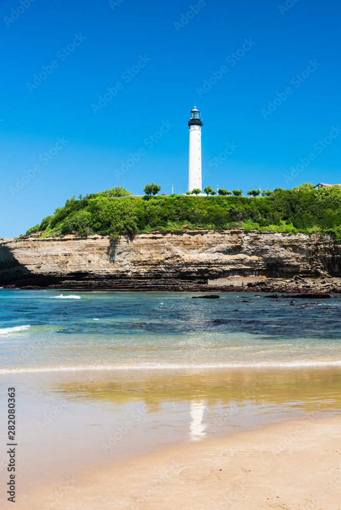 The lighthouse of Biarritz with its reflection in the water on the beach. Basque country of France