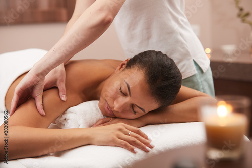Portrait of beautiful mixed-race woman lying on massage table and relaxing in luxury SPA, copy space