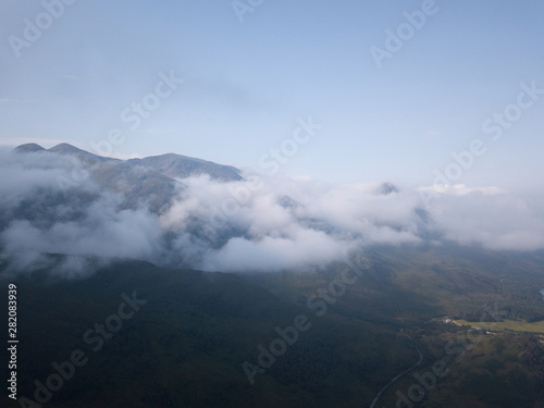 aerial view of loch leven near kinlochleven and glen coe in the argyll region of the highlands of scotland with a green island in the foreground and calm blue waters with misty mountains