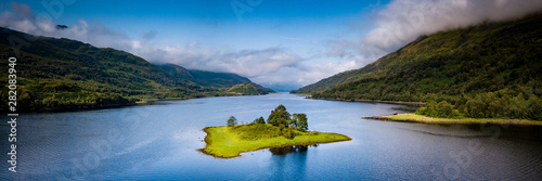 aerial view of loch leven near kinlochleven and glen coe in the argyll region of the highlands of scotland with a green island in the foreground and calm blue waters with misty mountains photo