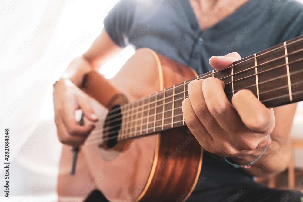 man's hands playing acoustic guitar, close up