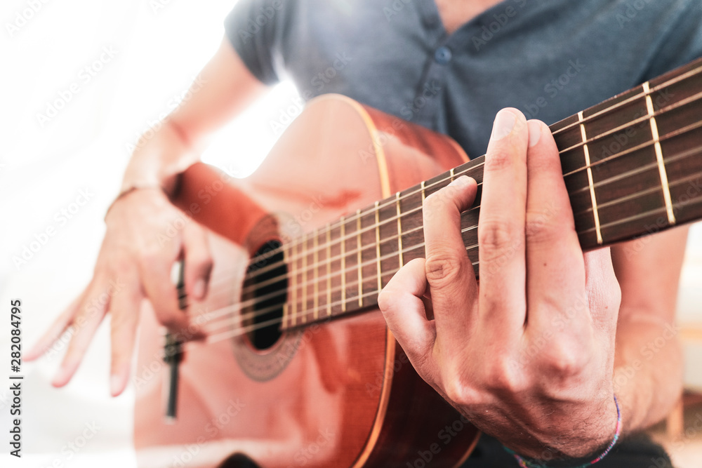 man's hands playing acoustic guitar, close up