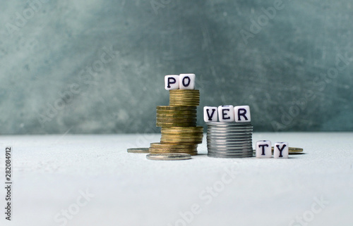 Poorness and lack of money concept with coins stack and poverty text on little cubes