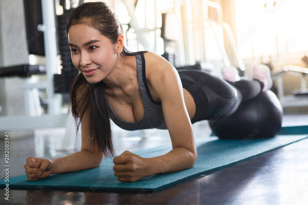 Beautiful Asian fitness young woman in sportswear doing plank with ball on mat in gym . sport Fit girl push up exercise in morning . healthy lifestyle concept. workout . training. endurance . Beautiful Asian fitness young woman in sportswear doing plank with ball on mat in gym . sport Fit girl push up exercise in morning . healthy lifestyle concept. workout . training. endurance .