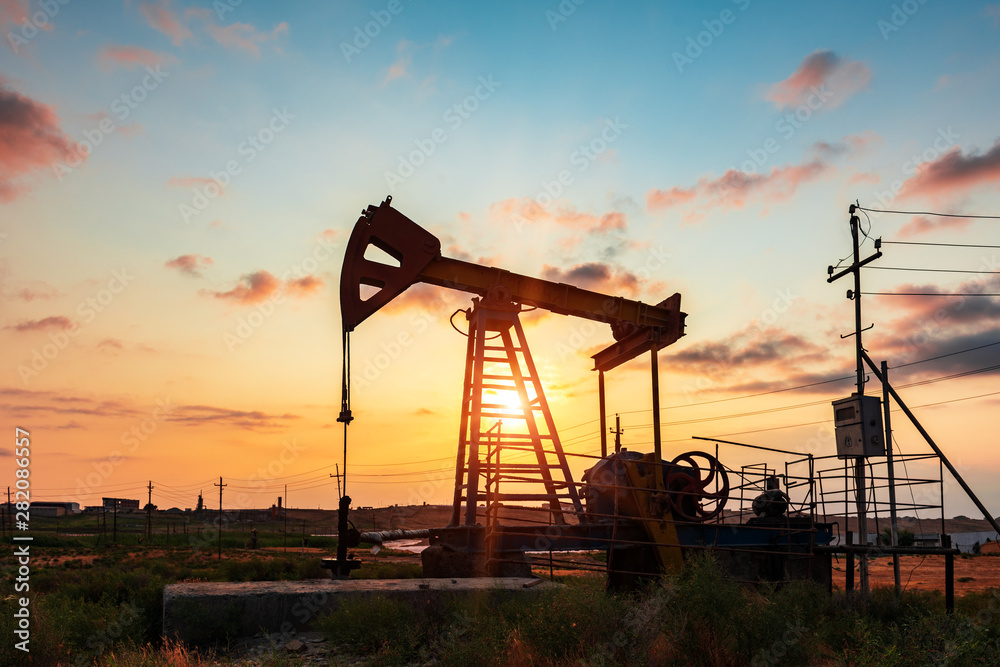 Oil rig pump against a colorful sunset sky Oil rig pump against a colorful sunset sky