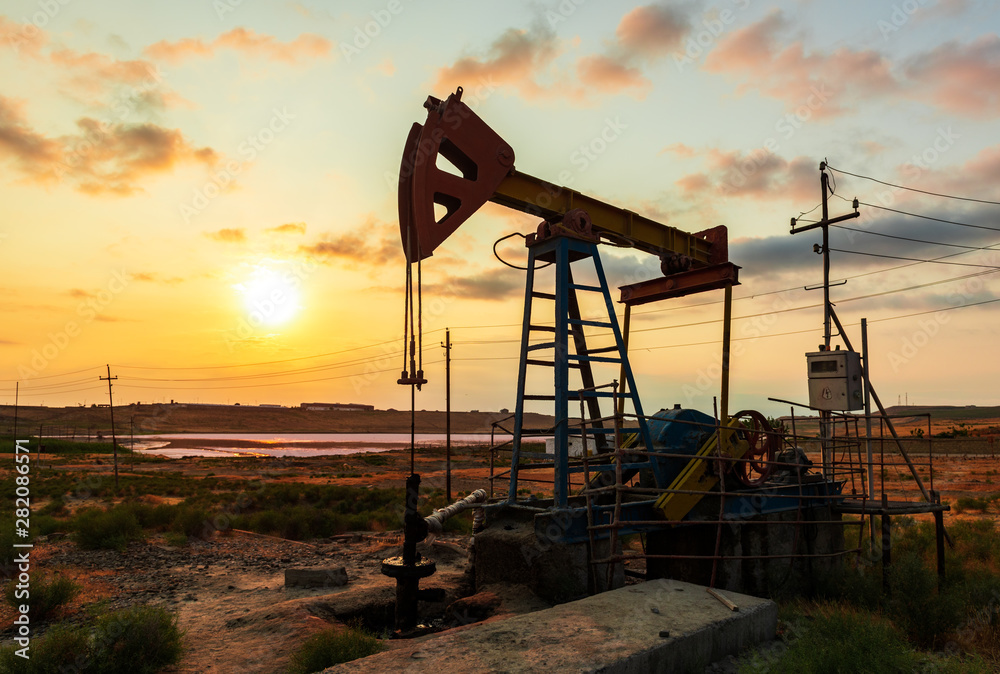 Oil rig pump against a colorful sunset sky Oil rig pump against a colorful sunset sky