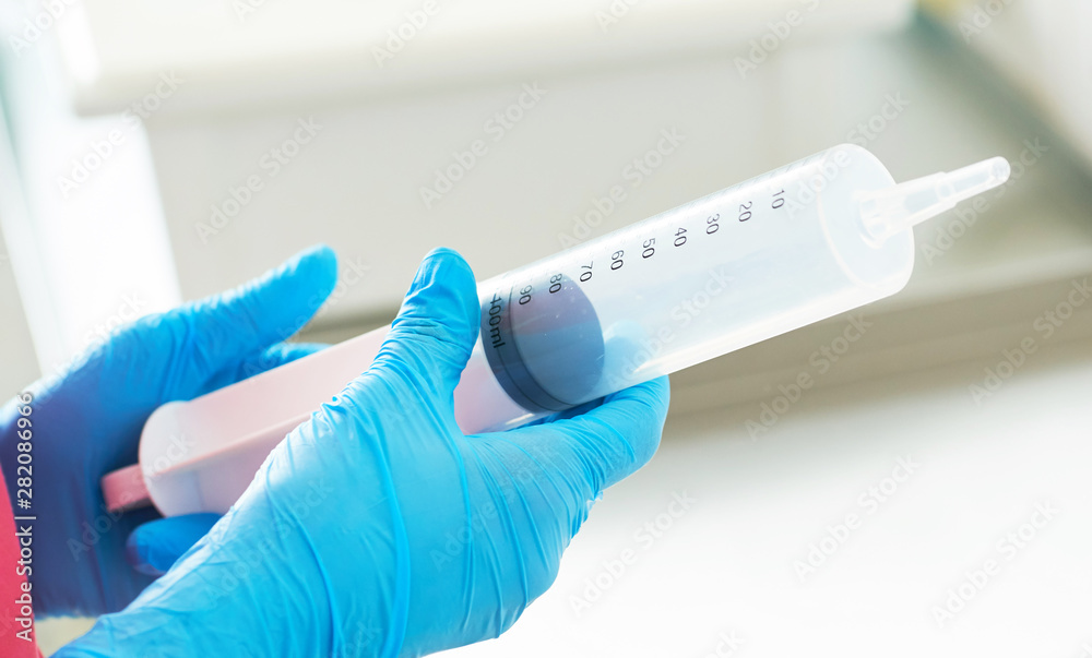 Syringe for gastric lavage in the hands of a nurse in the operating room. Nurse preparing medical instruments for operation. Syringe for gastric lavage in the hands of a nurse in the operating room. Nurse preparing medical instruments for operation.