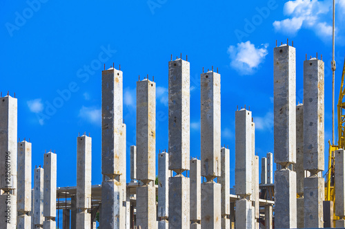 Vertical Reinforced Concrete Columns with Rebars at Construction Site, Blue Sky and White Clouds in Background. Real Estate, Residential Buildings Urban Mixed-Use Development Concept.