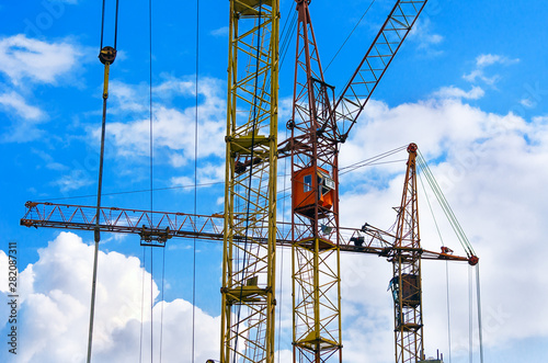 Yellow and Red Cranes against Blue Sky and Clouds. Real Estate, Residential Buildings Urban Mixed-Use Development Concept.