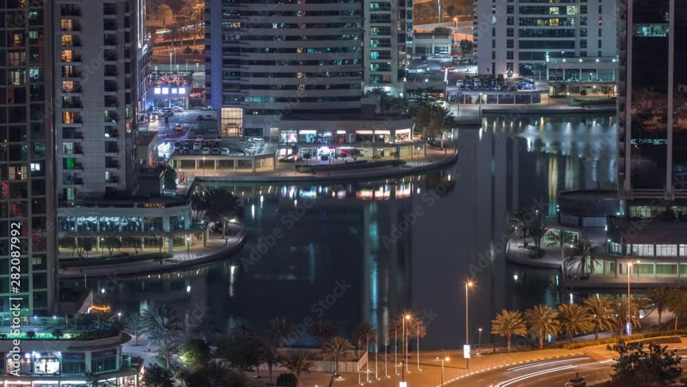 Jumeirah Lake Towers residential district aerial night timelapse near Dubai Marina. Illuminated modern skyscrapers reflected in water and traffic from above Jumeirah Lake Towers residential district aerial night timelapse near Dubai Marina. Illuminated modern skyscrapers reflected in water and traffic from above