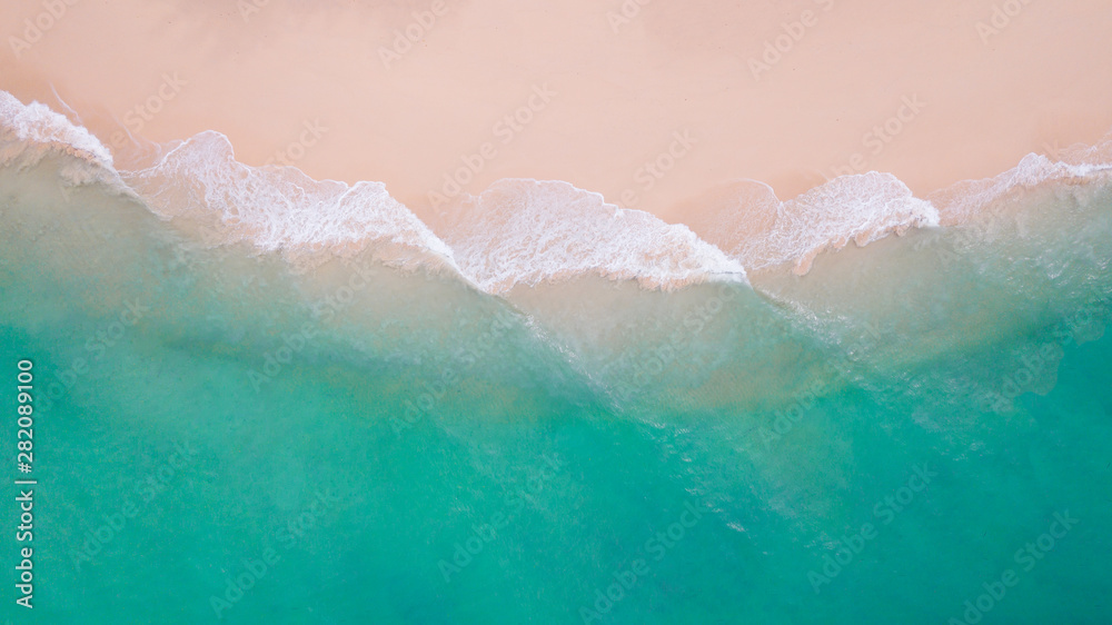 Fototapeta premium Beach top view. Aerial view sand beach wave foam from turquoise water on the tropical island