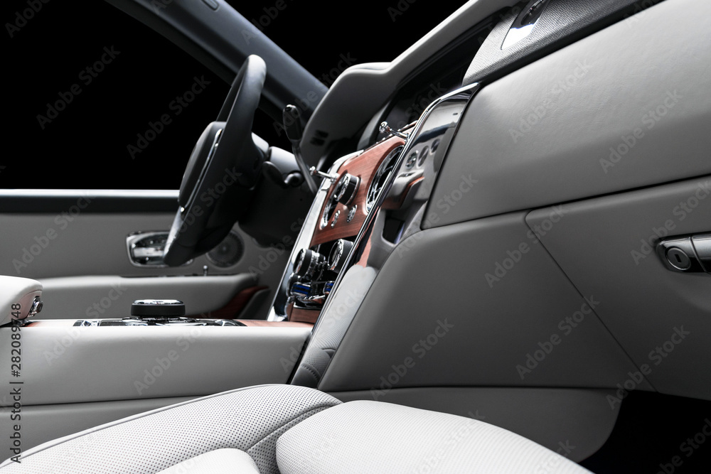 Modern luxury car white leather interior with natural wood panel. Part of leather car seat details with stitching. Interior of prestige modern car. White perforated leather. Car detailing. Car inside