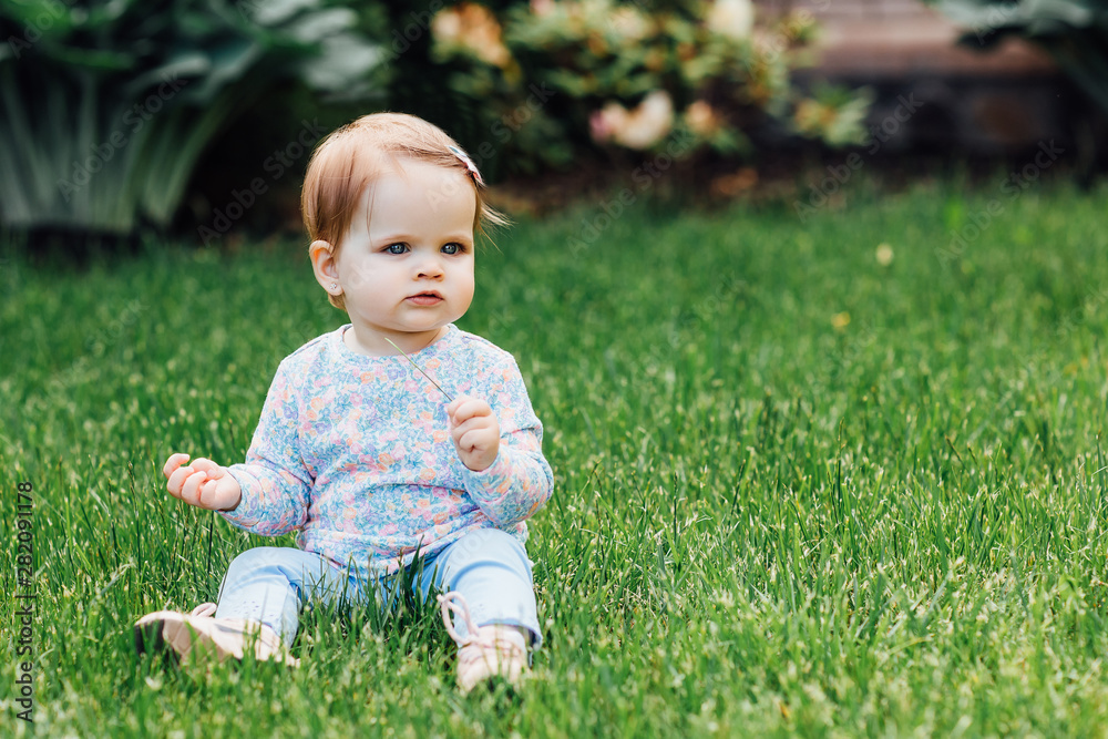 Outdoor portrait of a cute little girl in pretty wear siting on the garden grass. Outdoor portrait of a cute little girl in pretty wear siting on the garden grass.