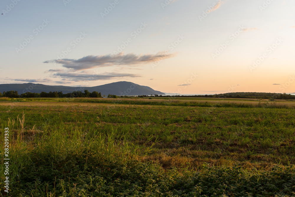 Horizontal view of the Cap Tourmente and the St. Lawrence River seen from the Saint-François village in the Island of Orleans during a summer sunrise, Quebec, Canada