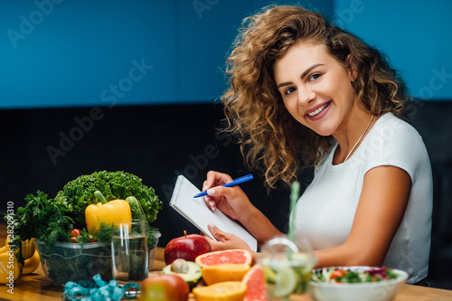 Nutritionist working in office. Doctor writing diet plan on table and using vegetables.