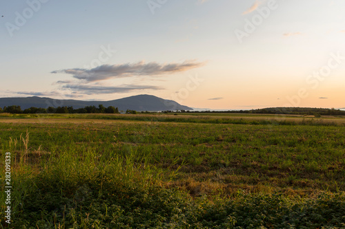 Horizontal view of the Cap Tourmente and the St. Lawrence River seen from the Saint-Fran  ois village in the Island of Orleans during a summer sunrise  Quebec  Canada