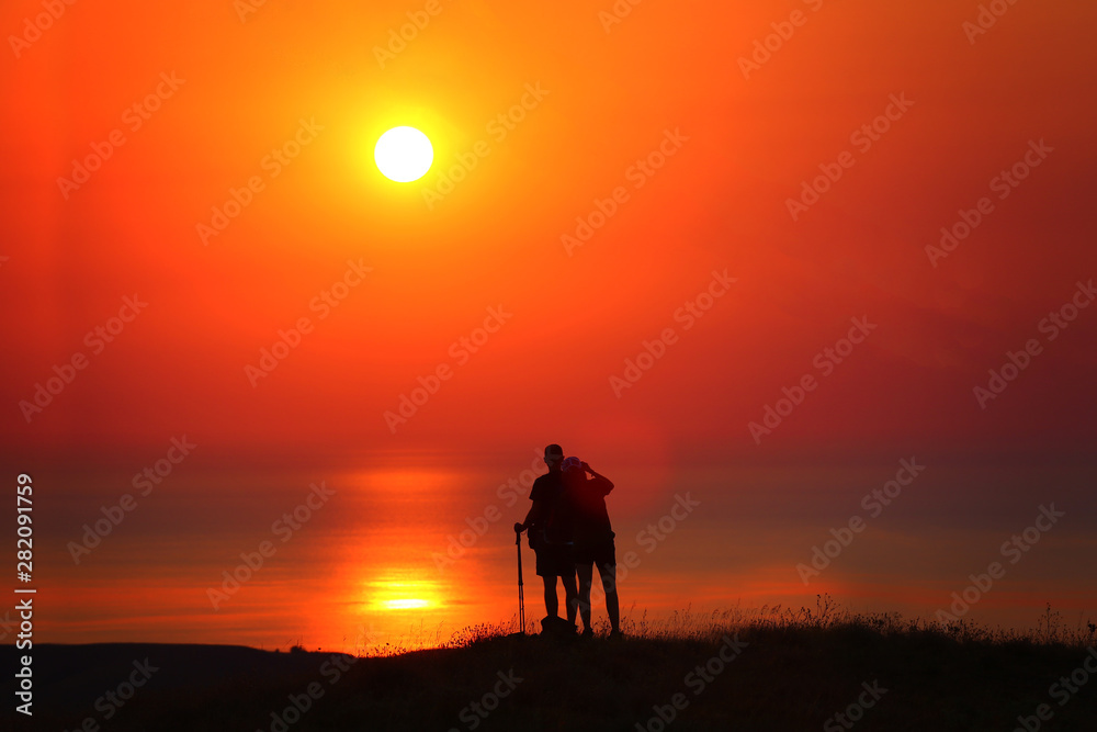Travelers together at sunrise stand by the sea
