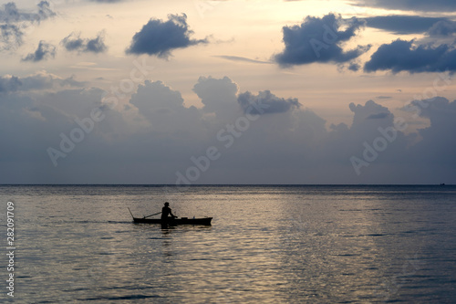 Silhouette of a man on a boat during sunset at sea.