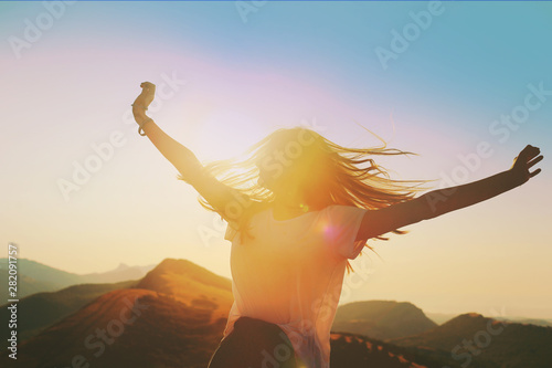 Girl on a background of mountains joyful spread her arms dancing at a height 2 photo