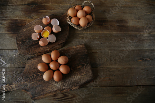 organic raw chicken eggs in a basket, egg shells and egg yolk on a wooden rustic board. Healthy eating concept. Easter. Flat lay, top view, with copy space for text and image.