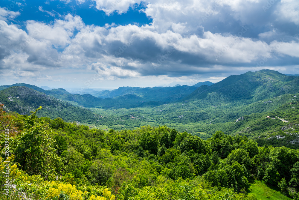 Fototapeta premium Montenegro, Endless wide green nature landscape view over skadar valley scenery of mountains and hills covered by trees and forest near skadar lake