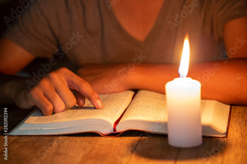 close up of Christian boys are reading and study bible In the room and lit candles to light, Religious concepts