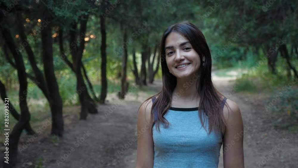 Portrait of young cute sportswoman in the beautiful park with green trees in the evening, Slow motion Portrait of young cute sportswoman in the beautiful park with green trees in the evening, Slow motion