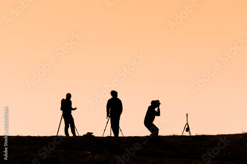 Silhouettes of hikers with backpacks enjoying sunset view from top of a mountain