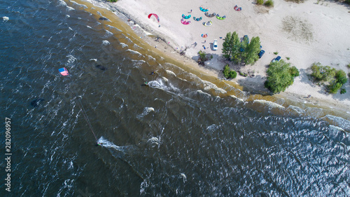Aerial view of many people who make kitesurfing activity  on beach 