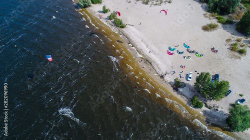 Aerial view of many people who make kitesurfing activity  on beach 