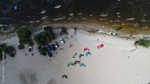 Aerial view of many people who make kitesurfing activity  on beach 